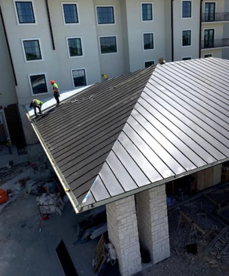 Crew installing standing seam metal roof panels on a commercial project in Forestville